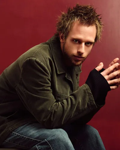 Cinematic color portrait of a man with dramatic low-key lighting and a soft-focus foreground element.